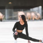 woman in black tank top and black leggings holding black and white nike shoes
