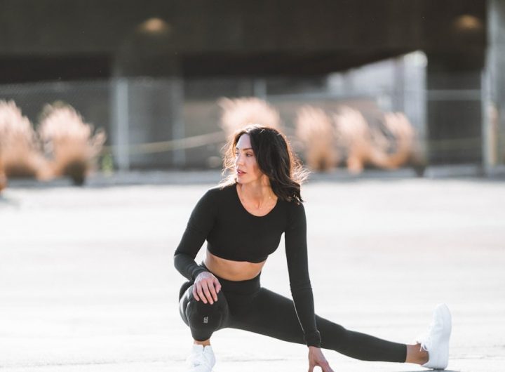 woman in black tank top and black leggings holding black and white nike shoes