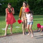 A joyous family experience in a lush Portugal park, featuring playful activities between young girls and adults.