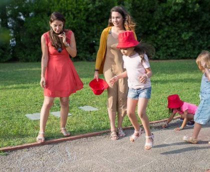 A joyous family experience in a lush Portugal park, featuring playful activities between young girls and adults.