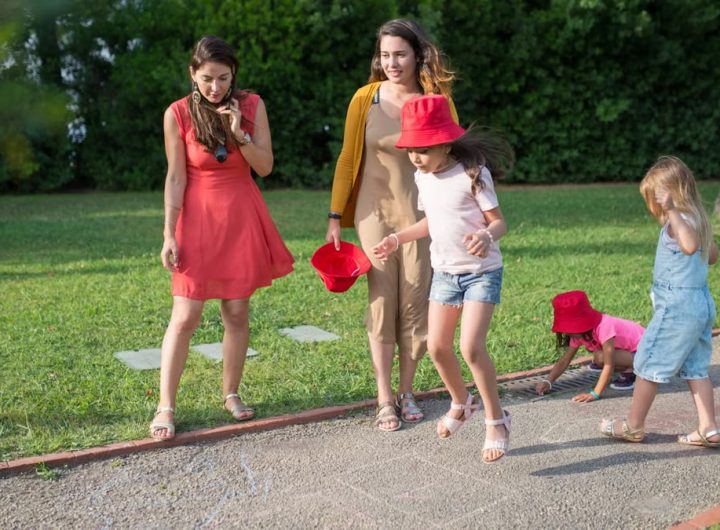 A joyous family experience in a lush Portugal park, featuring playful activities between young girls and adults.